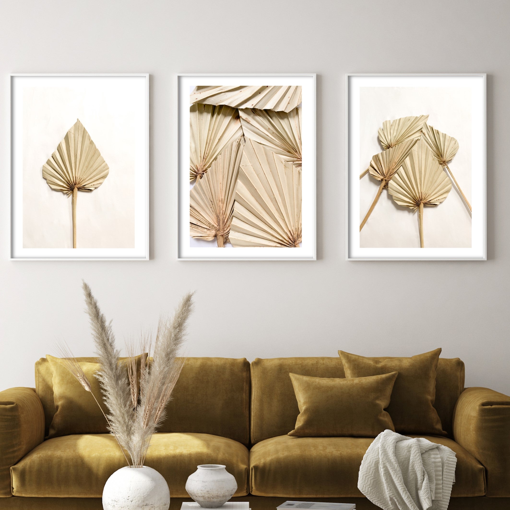 gold botanical dried palm leaf posters above velvet sofa